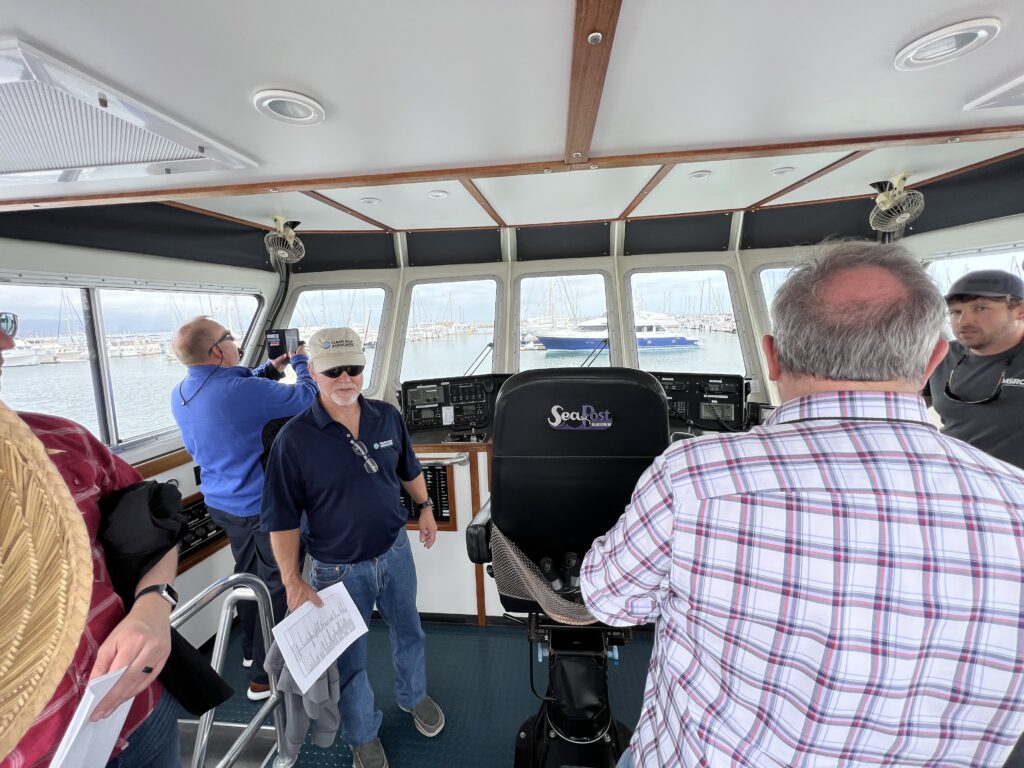 A group of people stand in the Helm of a boat