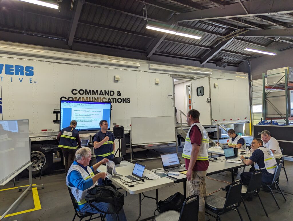 Planning Section Chief setting up for Tactics Meeting at CPBR TTX held at Clean Rivers Cooperative Operations Training Facility Bay 1 utilizing the Mobile Command and Communications trailer. Pictured with Unified Command.