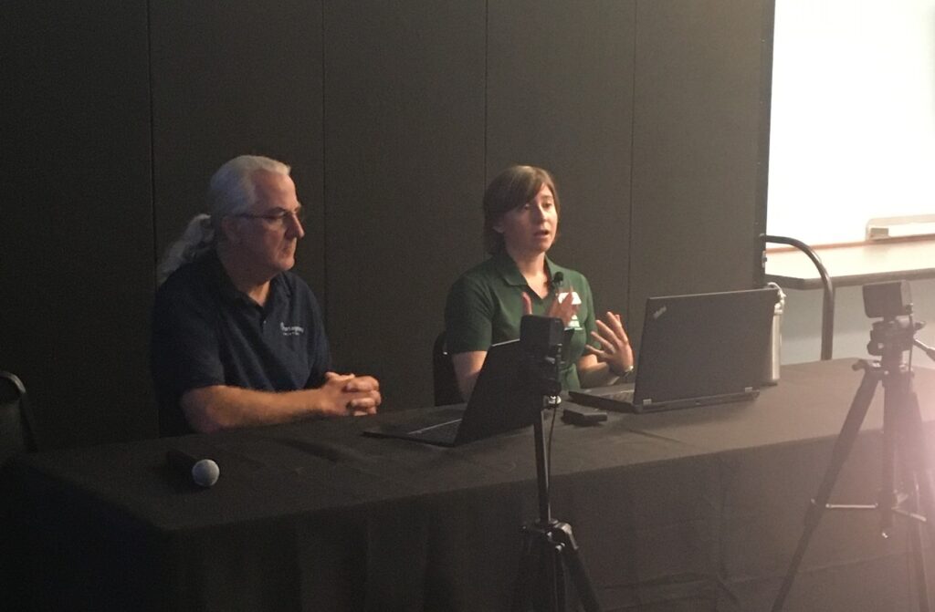Sara Behrman GIS Coordinator with Oregon Department of Environmental Quality speaking at the Tactics Conference. Also pictured John Newhoff , Senior Partner at Portage Bay Solutions.