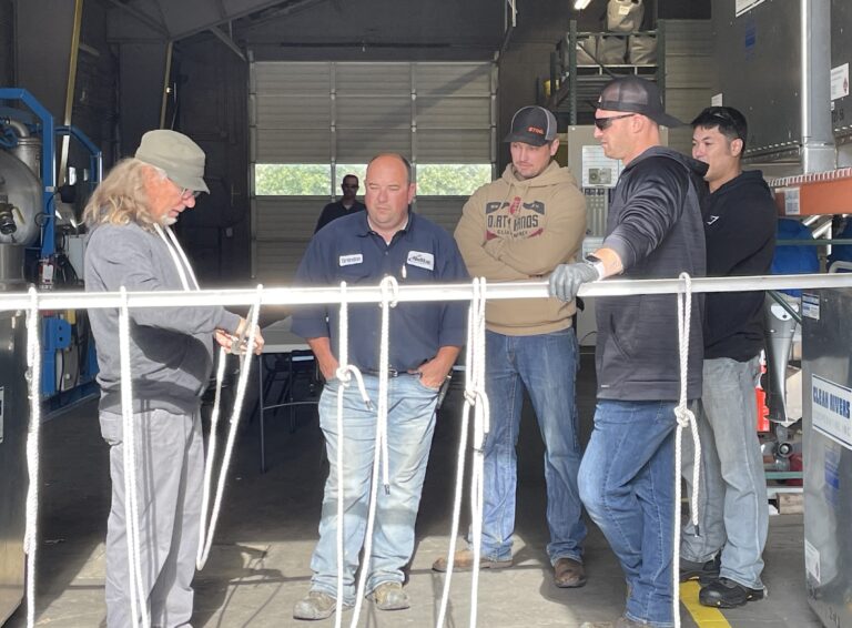 Four Members learn knot tying techniques from a response contractor at the 2023 Boom Rodeo Competition.